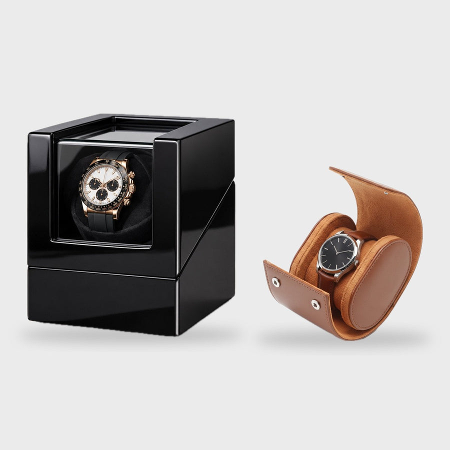 Le remontoir 1 montre laqué noir et l'étui de voyage 1 montre en simili-cuir cognac, côte à côte sur fond clair.