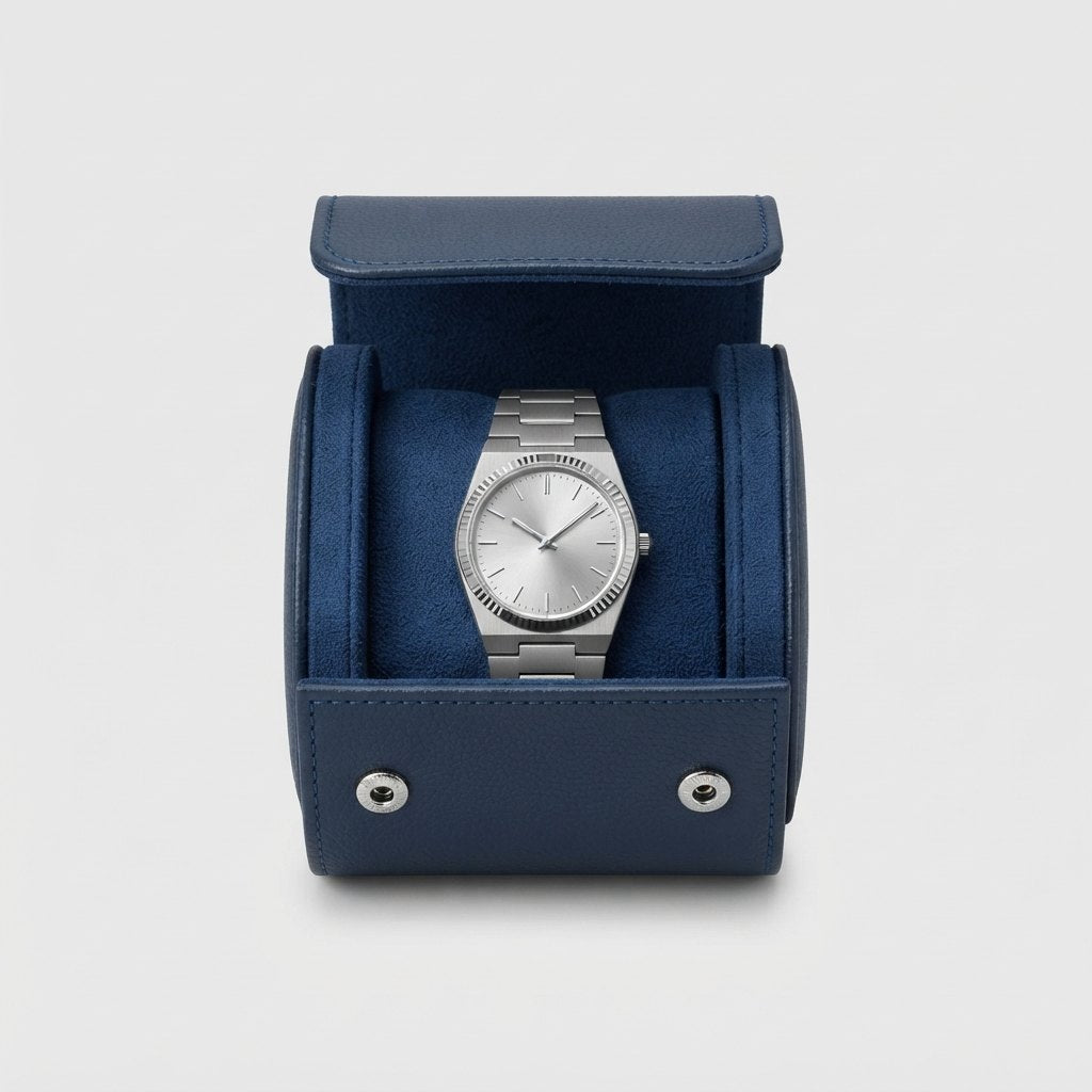 Étui vu de face, ouvert, montre bracelet acier posée dans le berceau en suédine bleu marine.