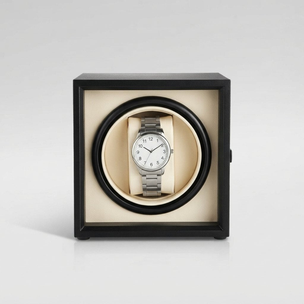 Cube noir, coussin crème vu de face, montre installée, fond clair.