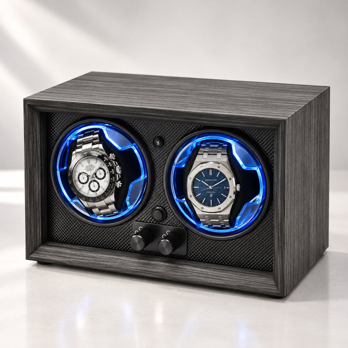 Caisson gris fumé vu de face, deux molettes, une montre chronographe et une montre à cadran bleu dans leurs anneaux bleus