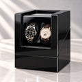Coffret laqué noir ouvert, deux montres côte à côte, fond clair