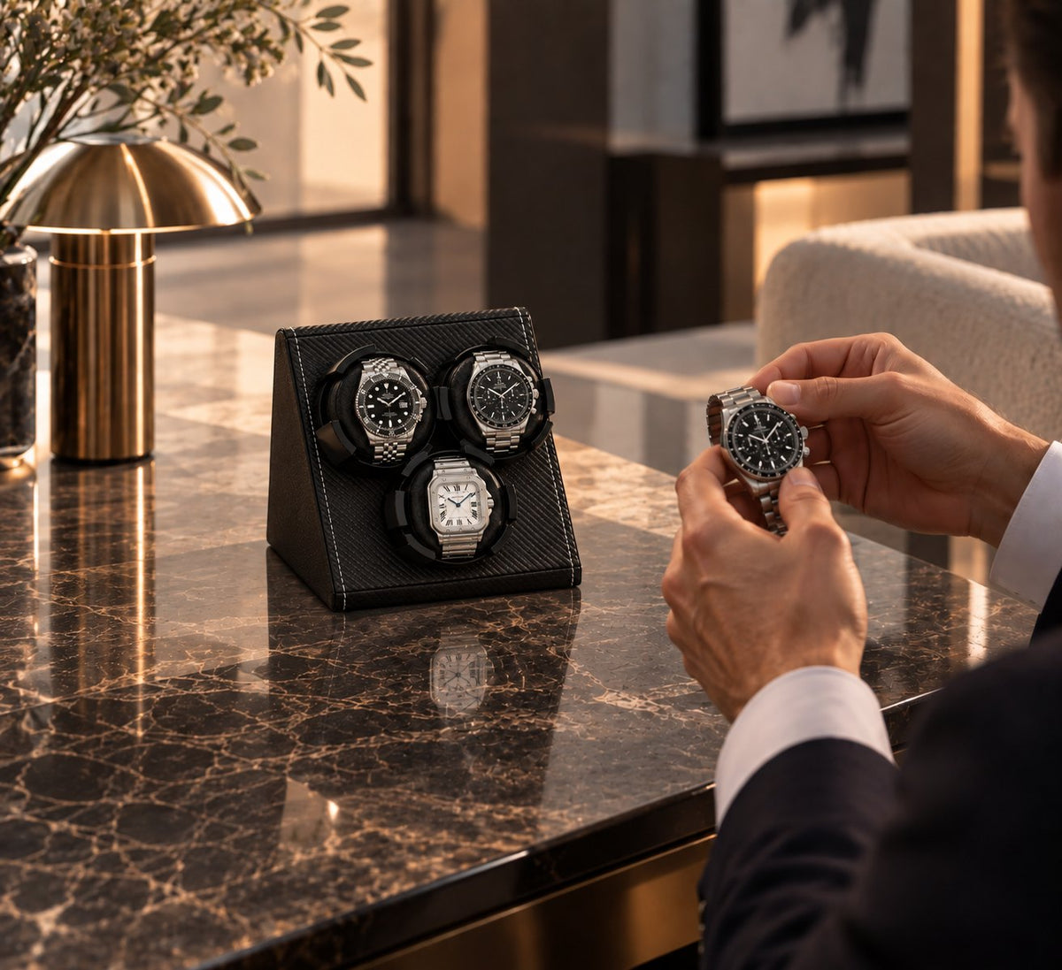 Une main ajuste une montre à côté de la console, trois montres déjà en place
